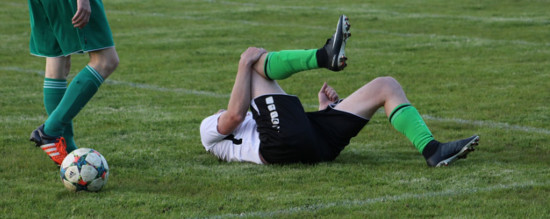 Fußballer liegt auf dem Spielfeld und hält sich das Knie.