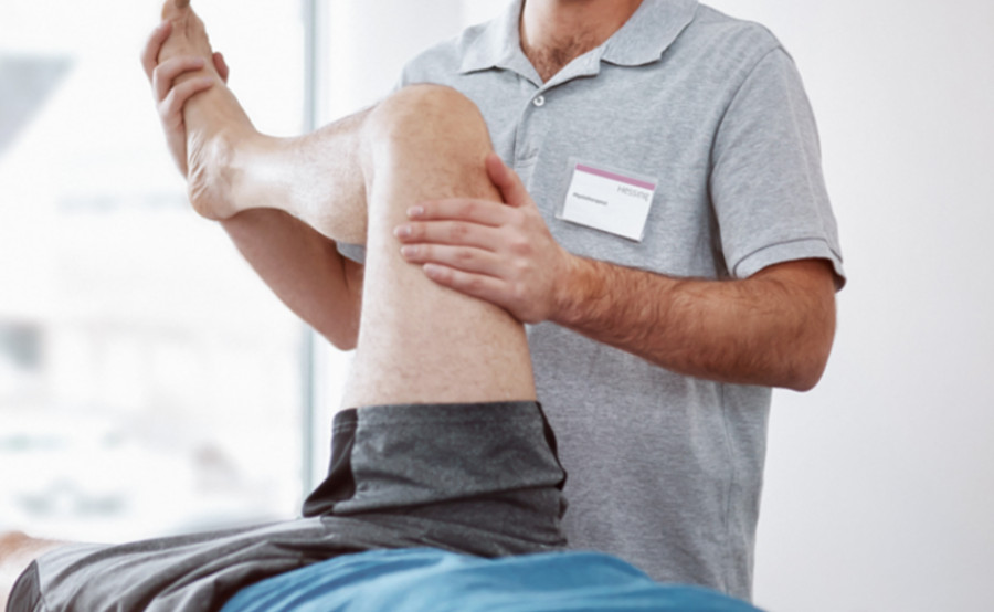 Physiotherapeut bewegt passiv das Bein eines Patienten.